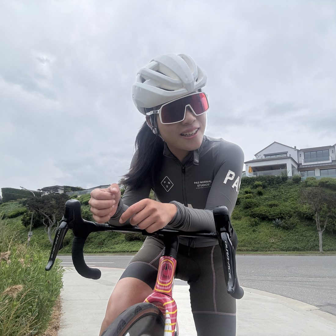 Weijun Li riding a road bike on the coast with the ocean behind